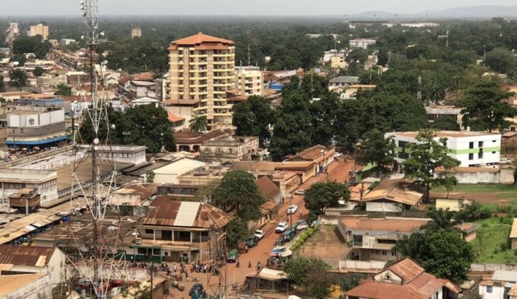 This aerial shot showcases a dense urban landscape with a mix of buildings, trees, and a prominent communication tower, likely in a developing region.