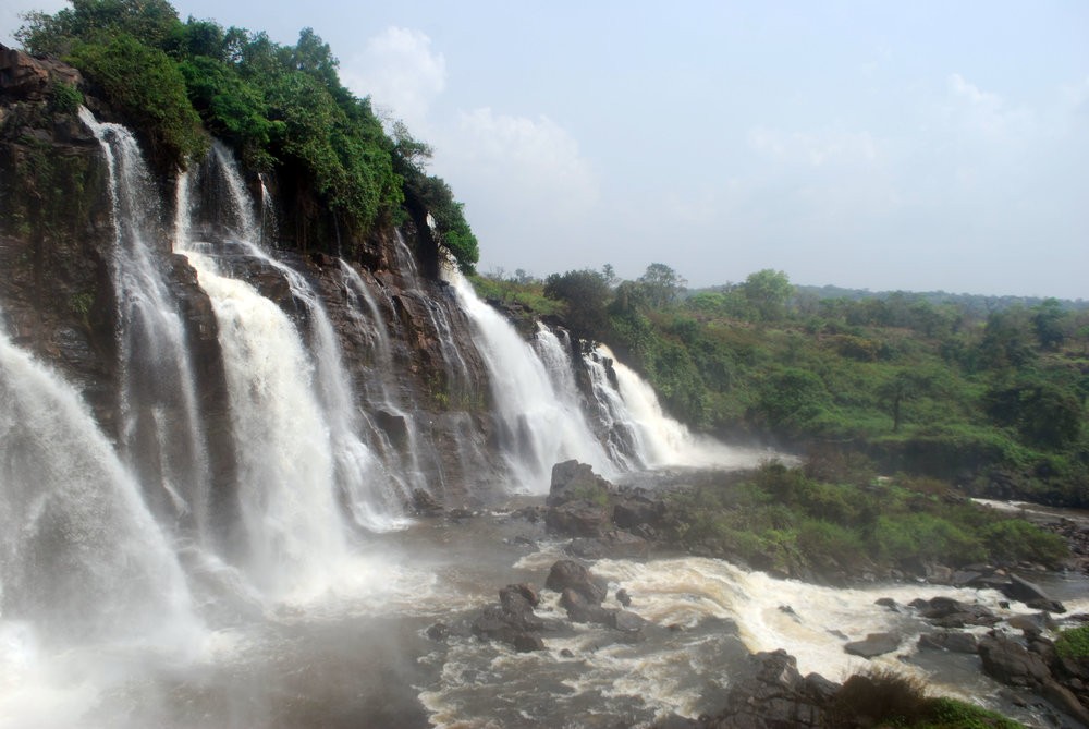 A stunning waterfall cascades down a rocky cliff, surrounded by lush greenery.