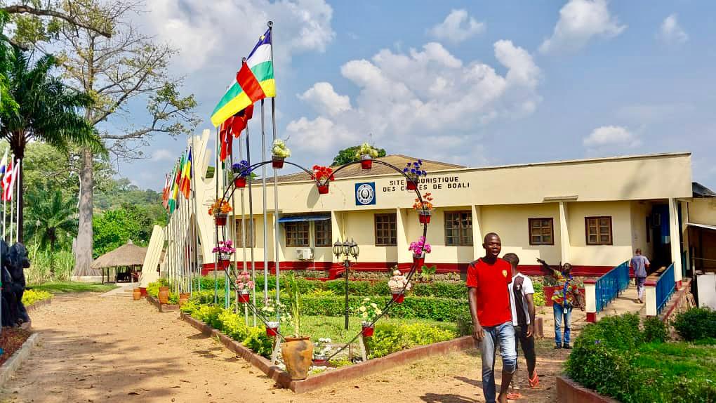 A colorful scene with flags and a heart-shaped floral display in front of a building labeled